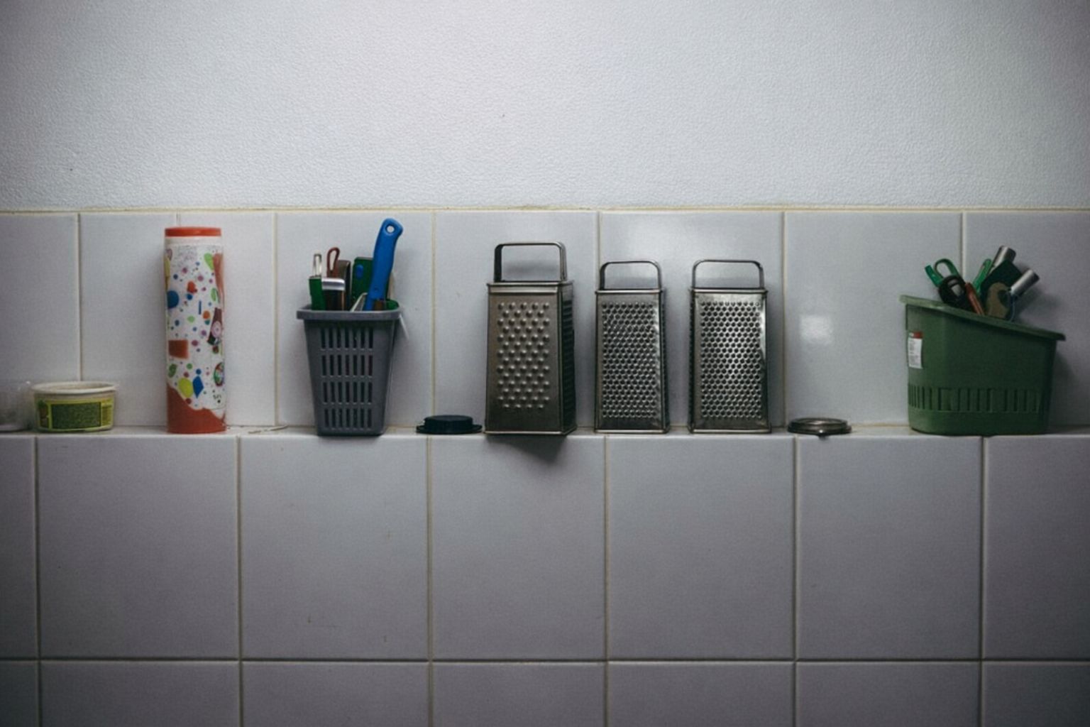 Baderomstilbehør og oppbevaringsbokser på en flislagt hylle.